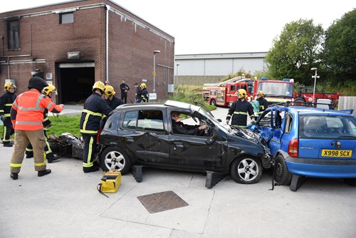 Image of road traffic collision with firefighters rescuing people stuck in a car.